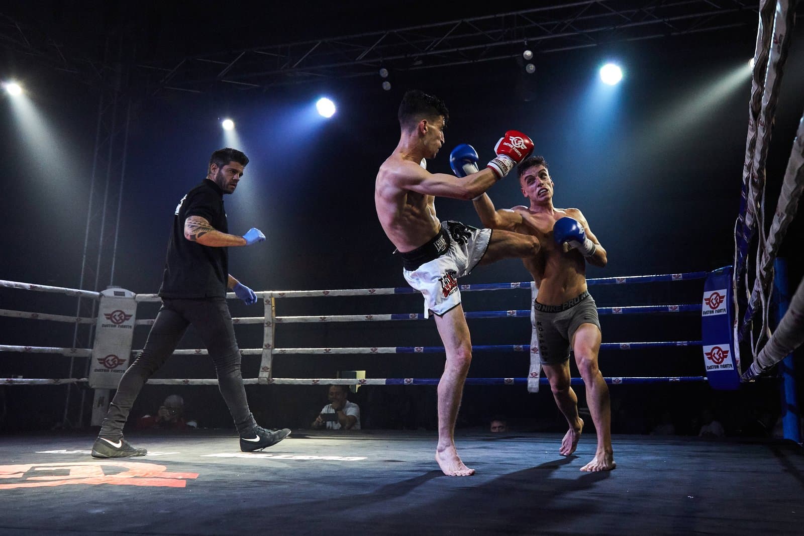 Combatiente de muay thai de Lions Fighters lanzando una patada en pleno combate, instante decisivo de la acción, cobertura de competición deportiva en Madrid