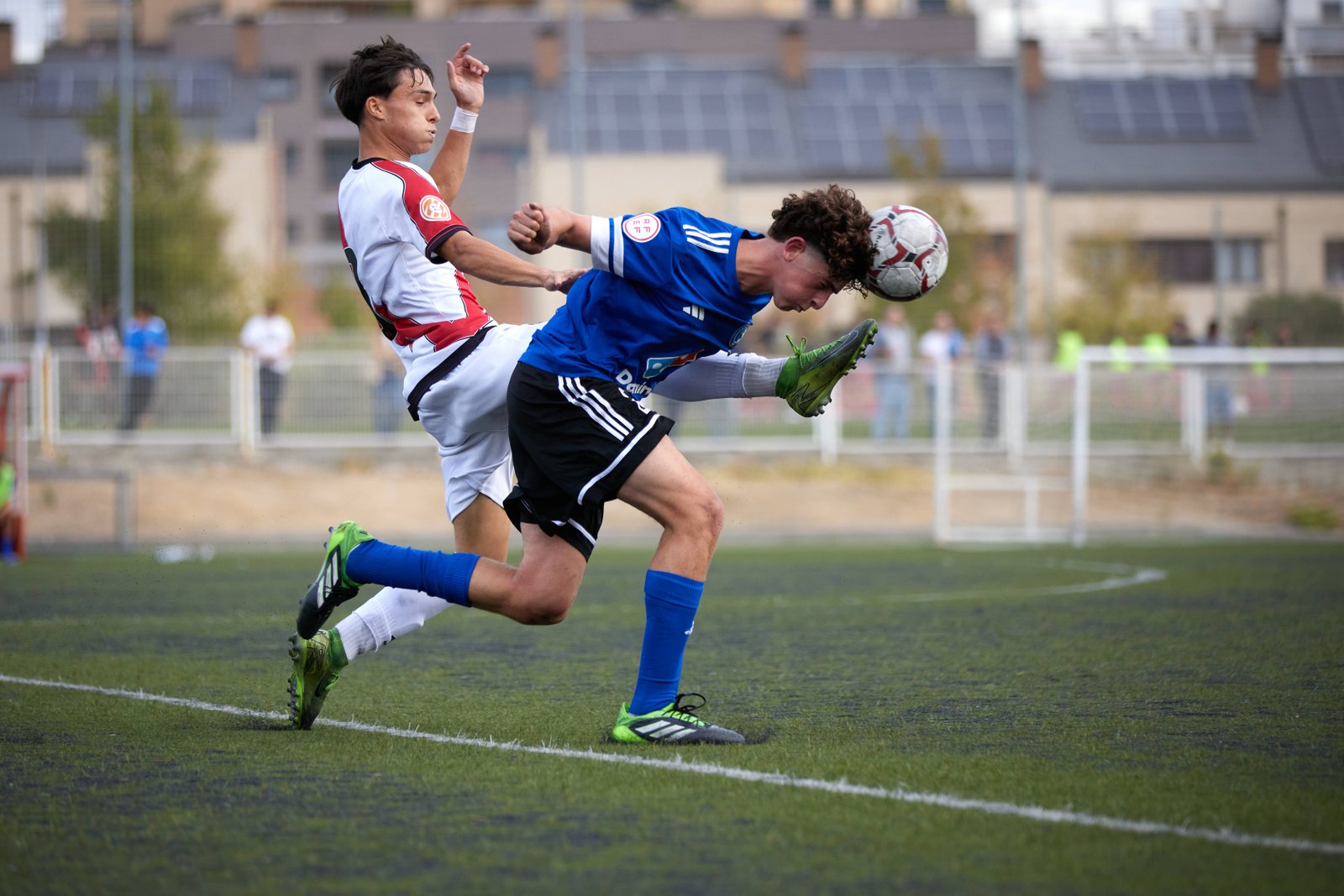 Jugador de fútbol despejando el balón en pleno partido, cobertura deportiva realizada por Carlos Ruiz