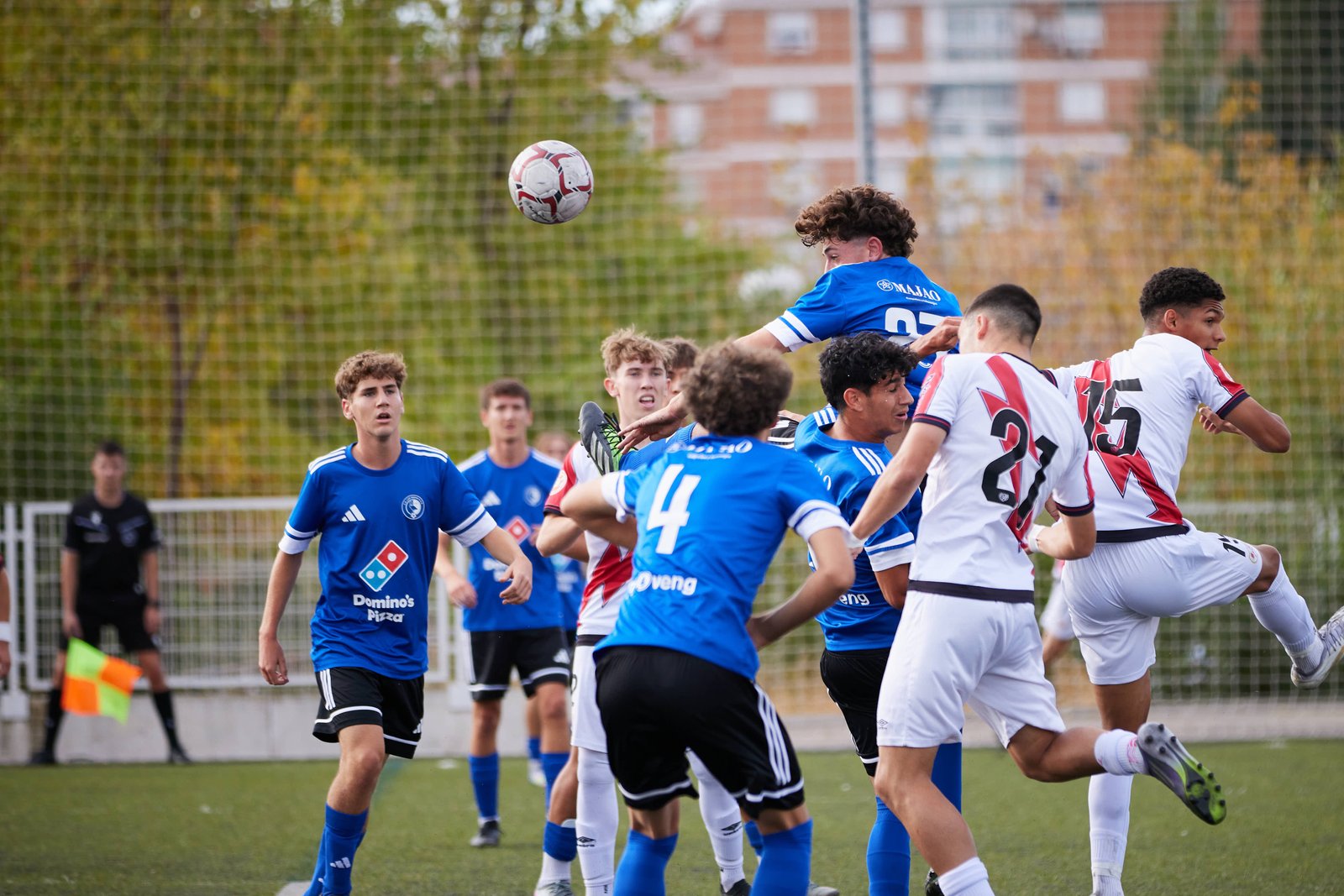 Defensa central del Juvenil de Las Rozas remata de cabeza ante el Rayo Vallecano en el área contraria.