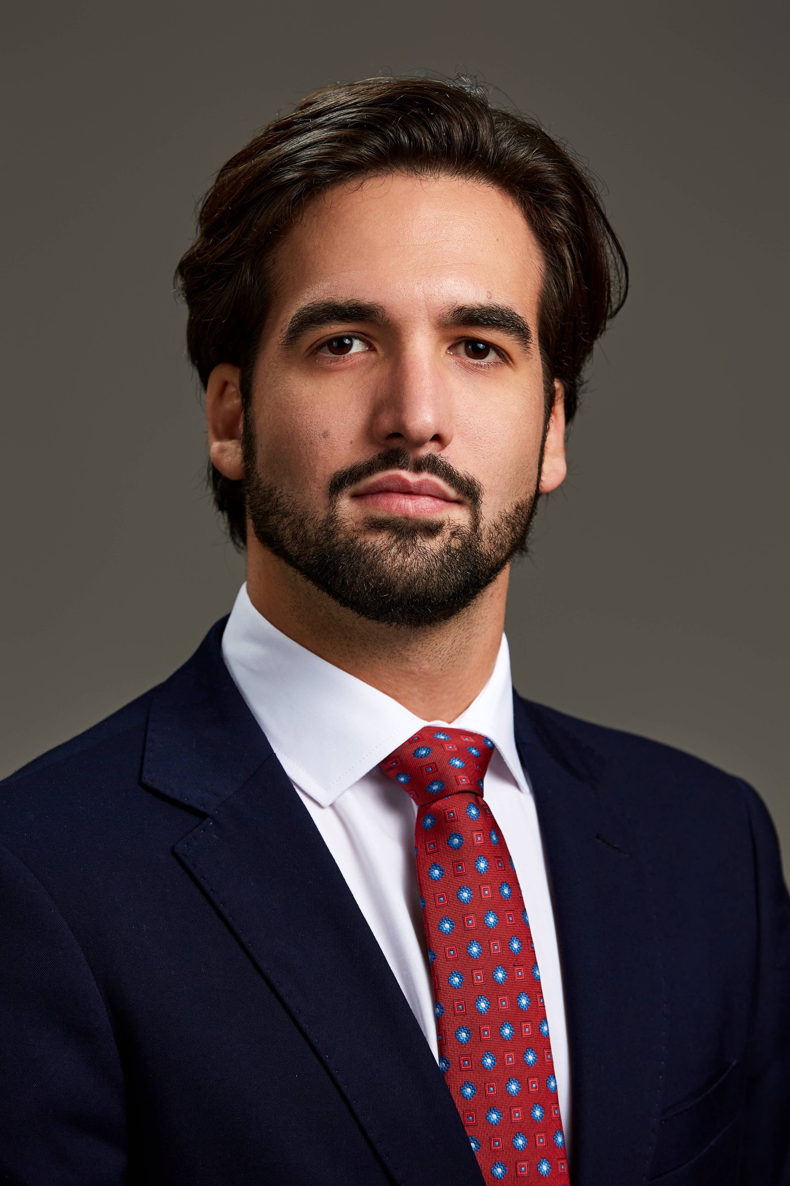 Headshot de abogado en Madrid con corbata roja y fondo oscuro