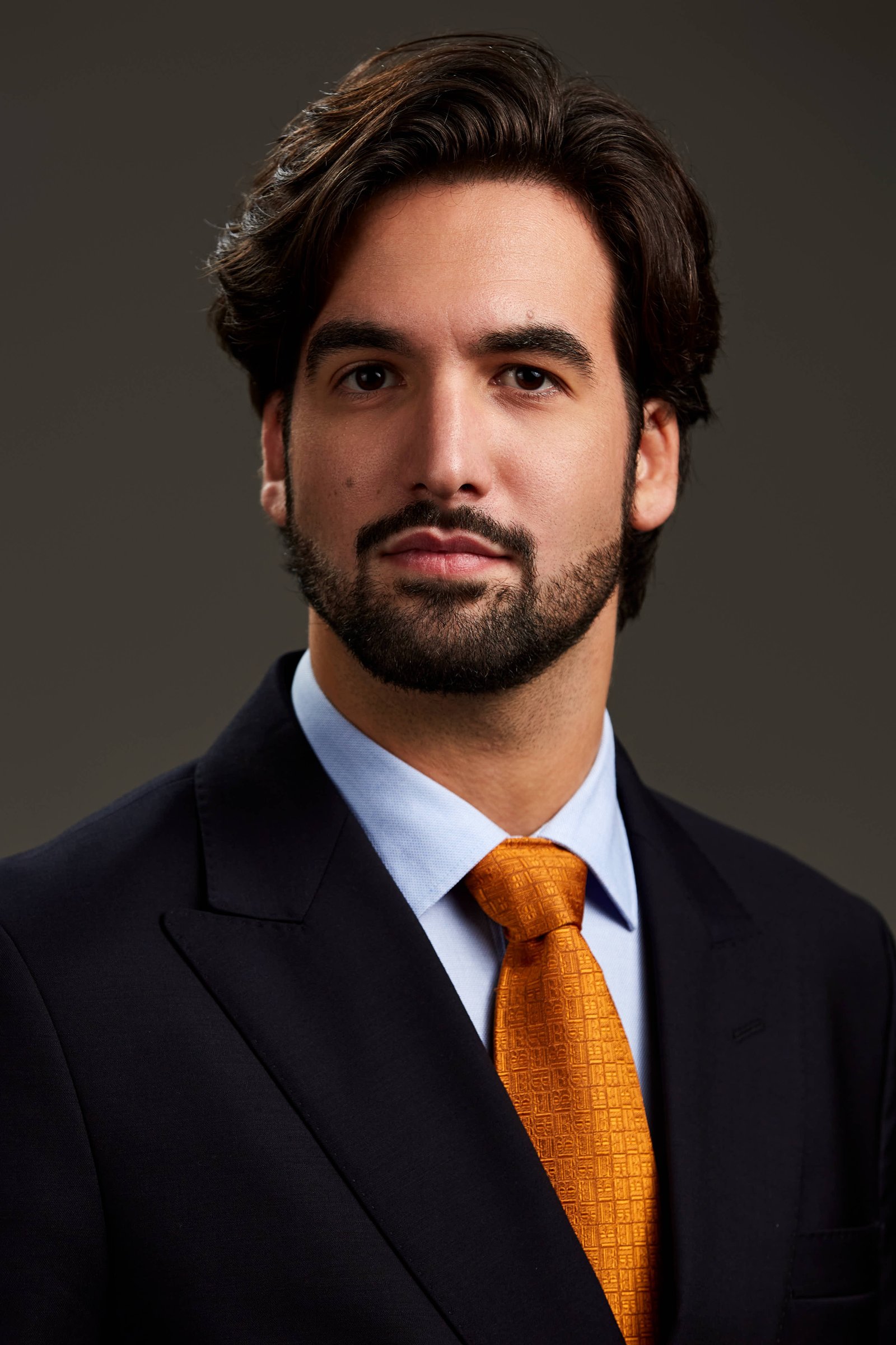 Retrato corporativo de abogado en estudio con corbata naranja y luz de volumen