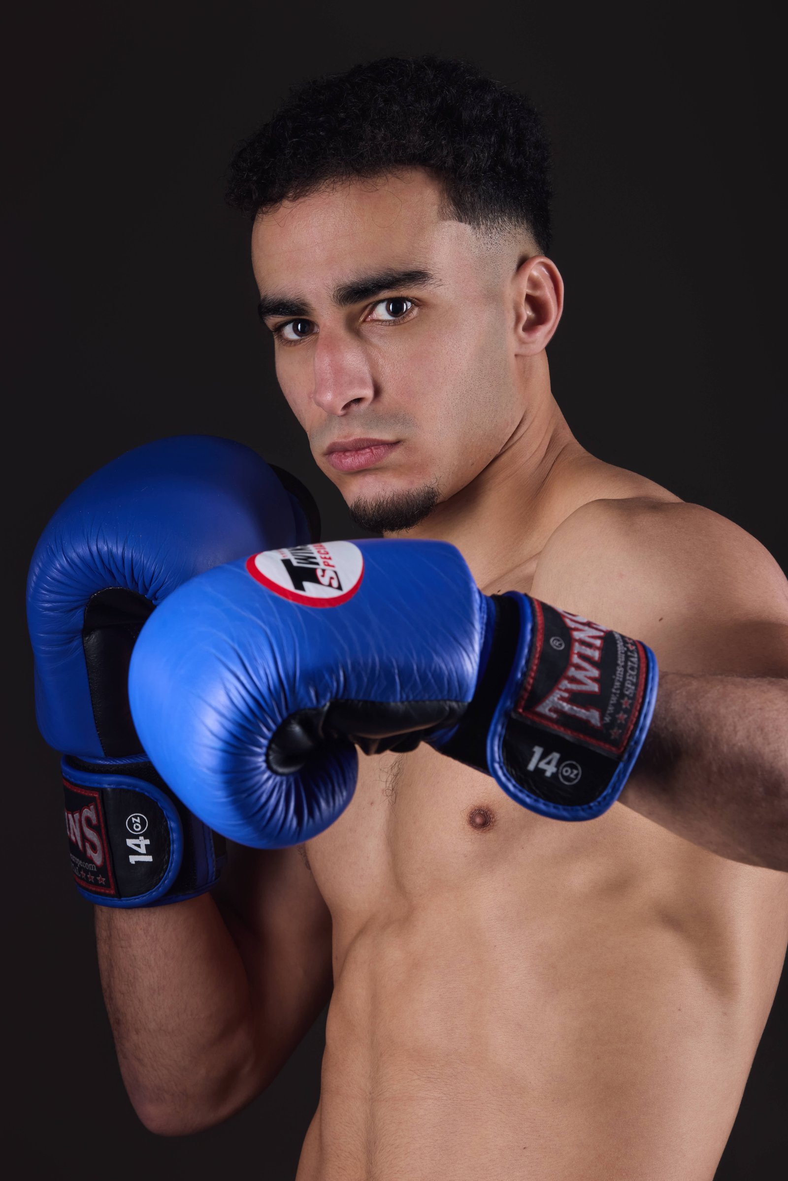 Primer plano de deportista de kickboxing K1 con expresión intensa y luz dramática.